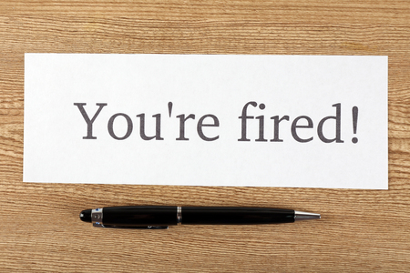 Message You're Fired on sheet of paper with pen on wooden table, top viewの写真素材