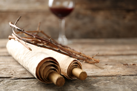 Crown of thorns, scroll and glass of wine on old wooden background