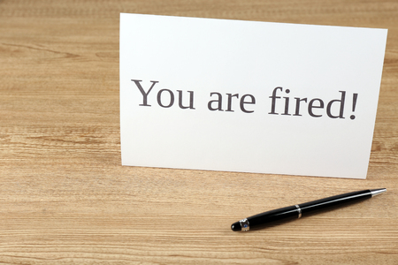 Message You're Fired with pen on wooden background