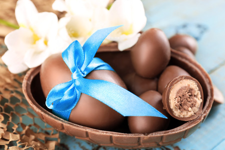 Chocolate Easter eggs with flowers on wooden table, closeup