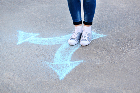 Female feet and drawing arrows on pavement background