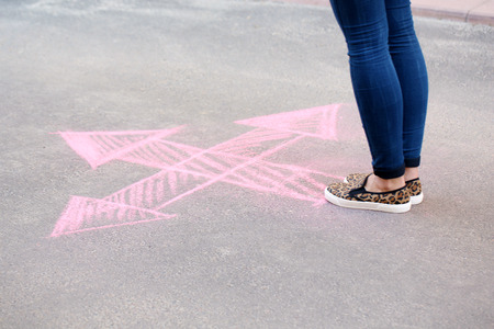 Female feet and drawing arrows on pavement backgroundの写真素材