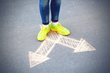 Female feet and drawing arrows on pavement backgroundの写真素材