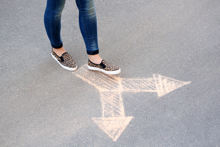 Female feet and drawing arrows on pavement backgroundの写真素材