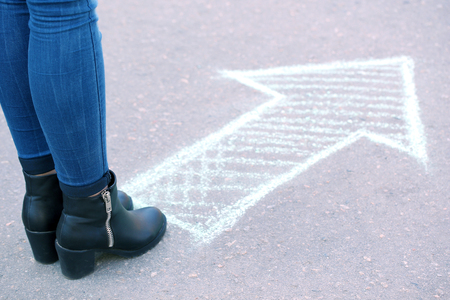 Female feet and drawing arrow on pavement backgroundの写真素材