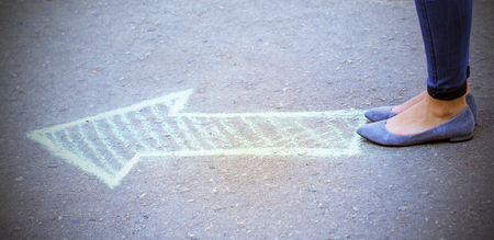 Female feet and drawing arrow on pavement backgroundの写真素材