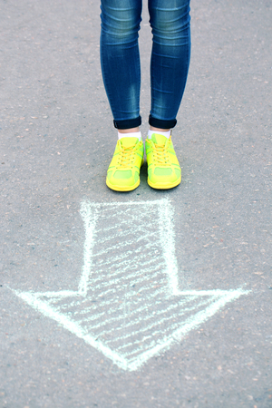 Female feet and drawing arrow on pavement backgroundの写真素材