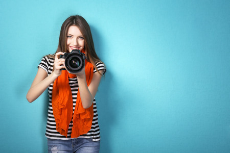 Young female photographer taking photos on blue background