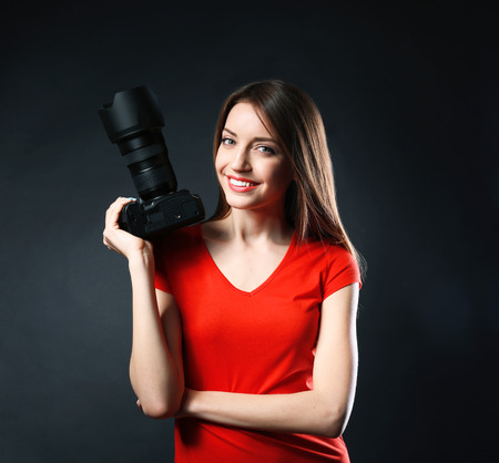 Young female photographer taking photos on black backgroundの写真素材