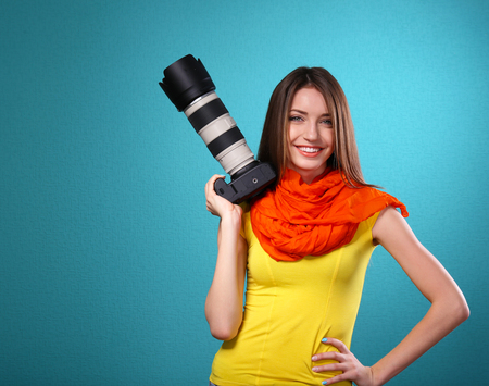 Young female photographer taking photos on blue backgroundの写真素材