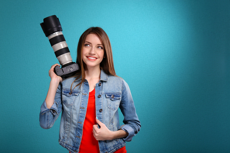 Young female photographer taking photos on blue backgroundの写真素材