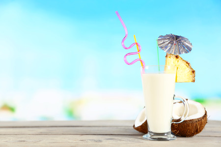 Glass of summer cocktail on wooden table on bright blurred background