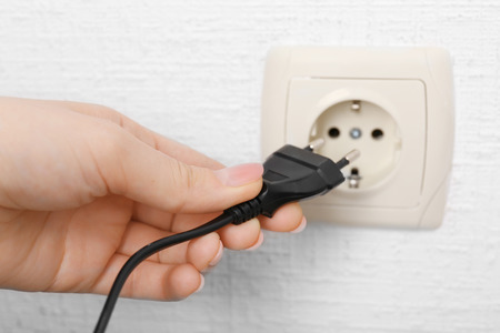 Hand putting plug in electricity socket close upの写真素材