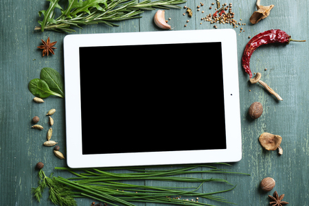 Digital tablet with fresh herbs and spices on wooden backgroundの写真素材