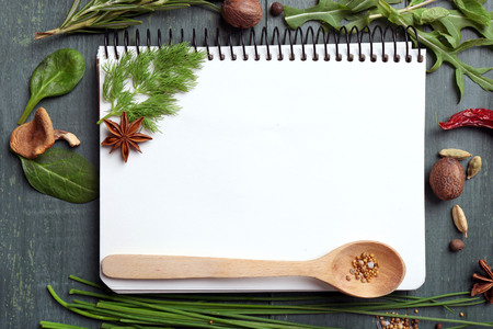 Open recipe book with fresh herbs and spices on wooden backgroundの写真素材