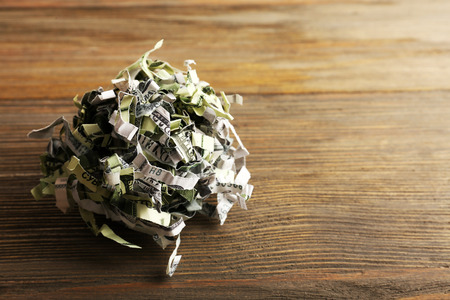 Destroyed money from shredder on wooden backgroundの写真素材