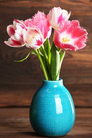 Beautiful tulips in vase on wooden backgroundの写真素材