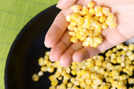 Hand holding frozen corn close upの写真素材