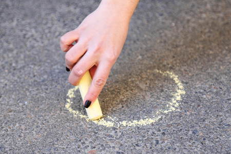 Girl drawing with chalk on asphaltの写真素材