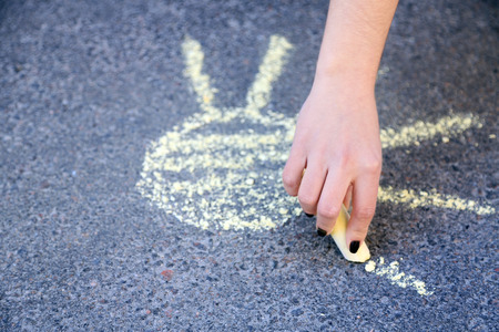 Girl drawing with chalk on asphaltの写真素材