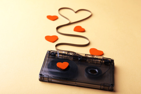 Audio cassette with magnetic tape in shape of heart on yellow backgroundの写真素材