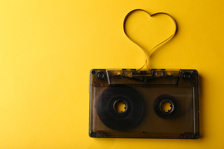 Audio cassette with magnetic tape in shape of heart on yellow backgroundの写真素材
