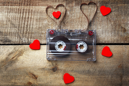 Audio cassette with magnetic tape in shape of hearts on wooden backgroundの写真素材
