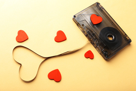 Audio cassette with magnetic tape in shape of heart on yellow backgroundの写真素材