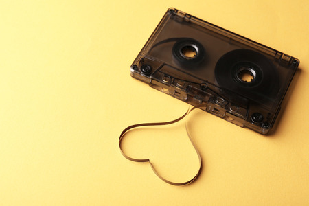 Audio cassette with magnetic tape in shape of heart on yellow backgroundの写真素材