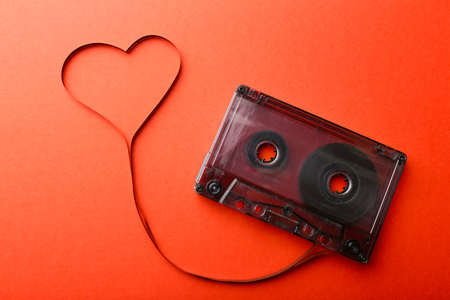 Audio cassette with magnetic tape in shape of heart on red backgroundの写真素材