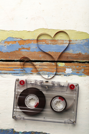 Audio cassette with magnetic tape in shape of heart on wooden backgroundの写真素材