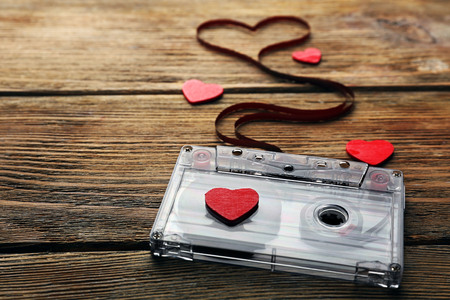 Audio cassette with magnetic tape in shape of heart on wooden backgroundの写真素材