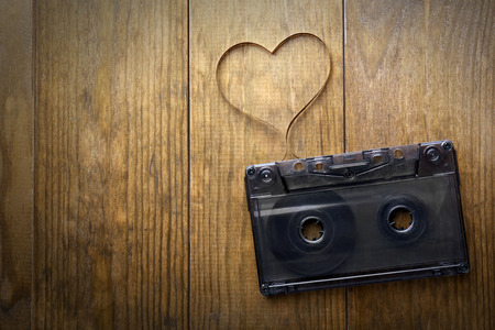 Audio cassette with magnetic tape in shape of heart on wooden backgroundの写真素材