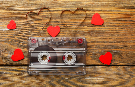 Audio cassette with magnetic tape in shape of hearts on wooden backgroundの写真素材