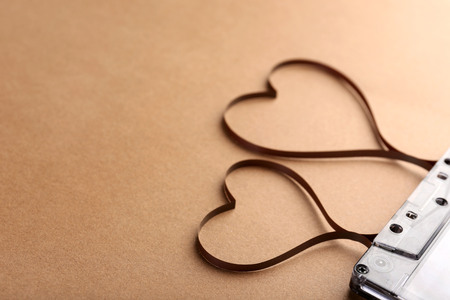 Audio cassette with magnetic tape in shape of hearts on brown backgroundの写真素材