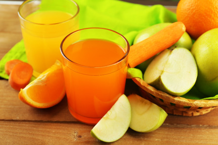 Glass of healthy fresh juice of apples and carrots on wooden backgroundの写真素材