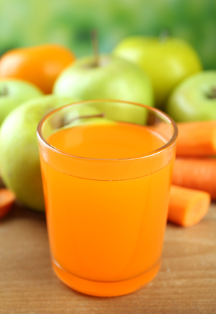 Glass of healthy fresh juice of apples and carrots on wooden backgroundの写真素材