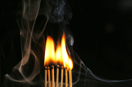 Burning matches in smoke on black backgroundの写真素材