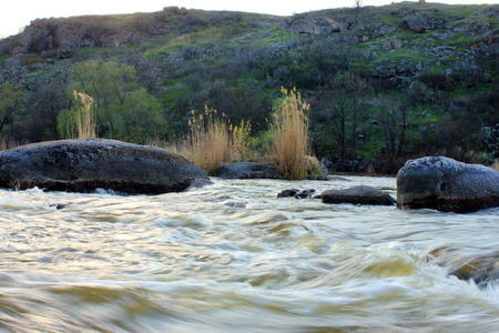Spring landscape with river, stones and treesの写真素材