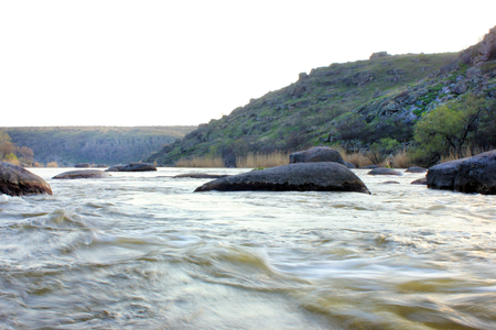Spring landscape with river, stones and treesの写真素材