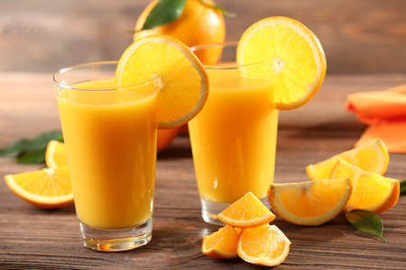 Orange juice on table on wooden backgroundの写真素材