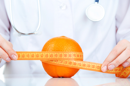 Nutritionist doctor with fruit and measuring tape, closeupの写真素材