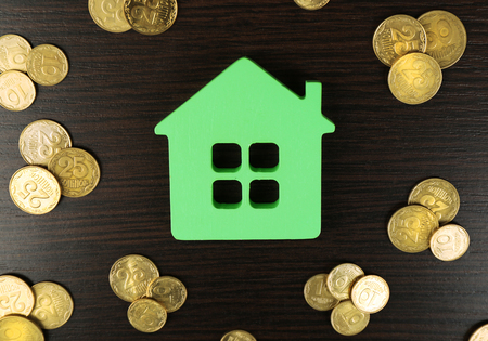 Model of house with coins on wooden table, closeupの写真素材