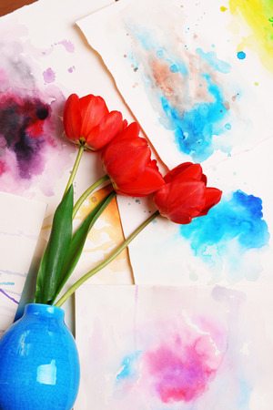 Red tulips in vase on watercolor sketches background top viewの写真素材