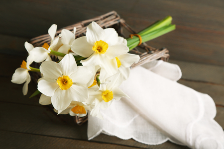 Fresh narcissus with wicker basket on wooden backgroundの写真素材