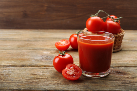Glass of fresh tomato juice on wooden backgroundの写真素材