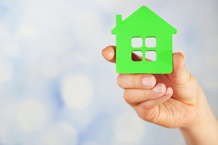 Female hand with model of house on blurred backgroundの写真素材