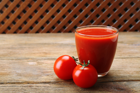 Glass of fresh tomato juice on wooden backgroundの写真素材