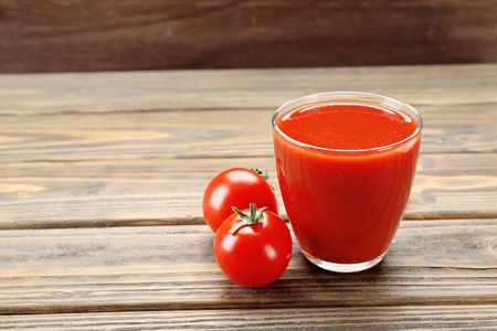 Glass of fresh tomato juice on wooden backgroundの写真素材