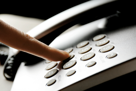Finger pressing number button on telephone to make a call, close upの写真素材